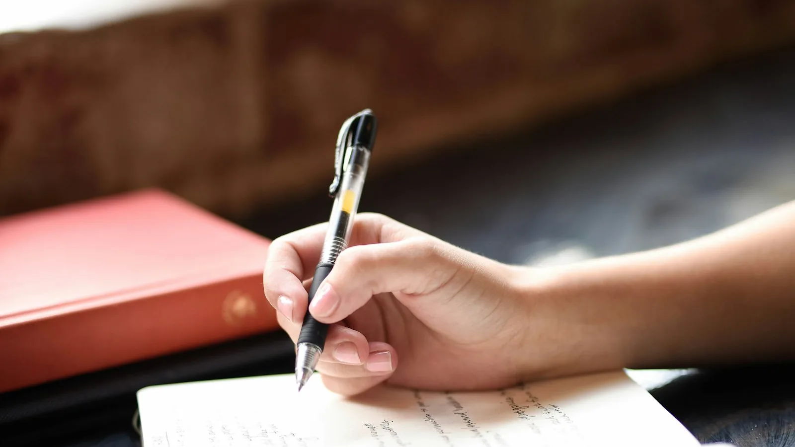 A hand writing notes on paper with a pen