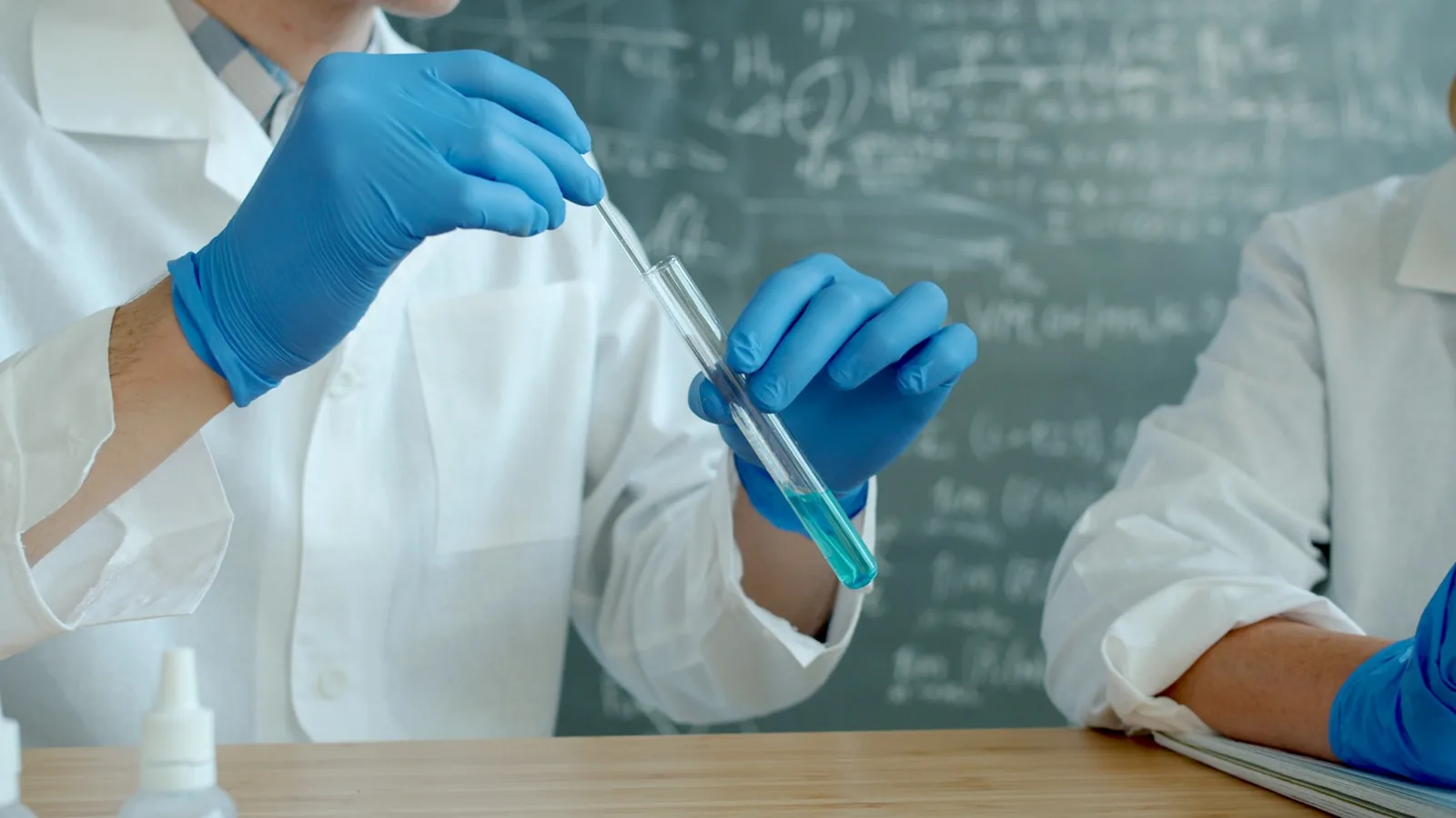 Two scientists in lab coats working with a test tube together